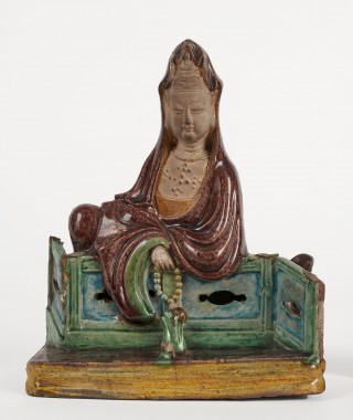 Figurka bogini Guanyin siedzącej przy ogrodzeniu