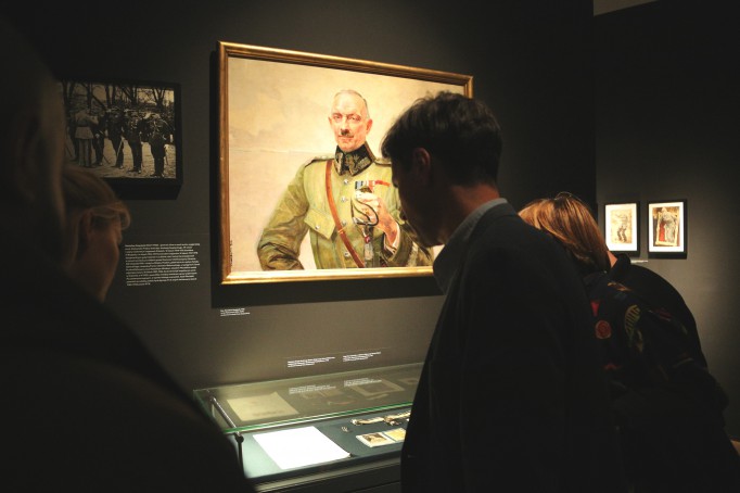 Wystawa "Virtuti Militari" Kilka osób stoi przed szklaną gablotą i ogląda pamiątki.