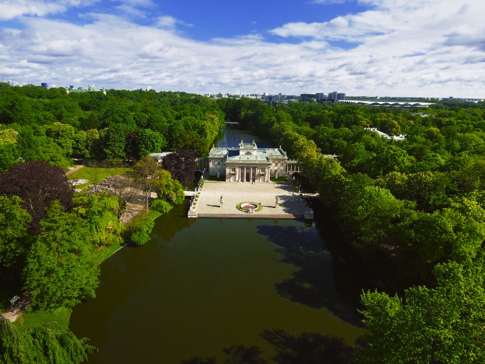 Widok na Pałac na Wyspie w otoczeniu drzew i wody z lotu ptaka. 