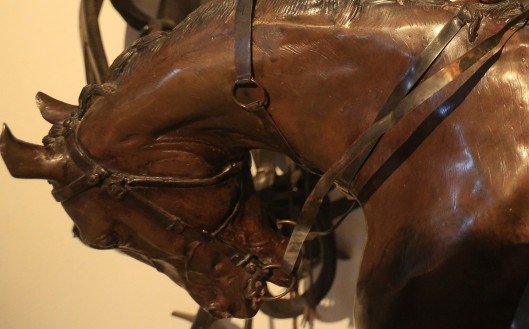 Rzeźba z brązu przedstawiająca pochyloną głowę konia. 