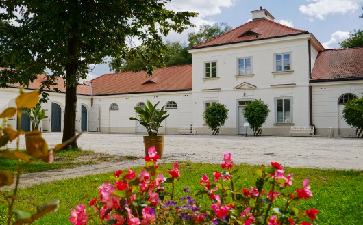 Budynek Stajni Kubickiego w otoczeniu zieleni. 