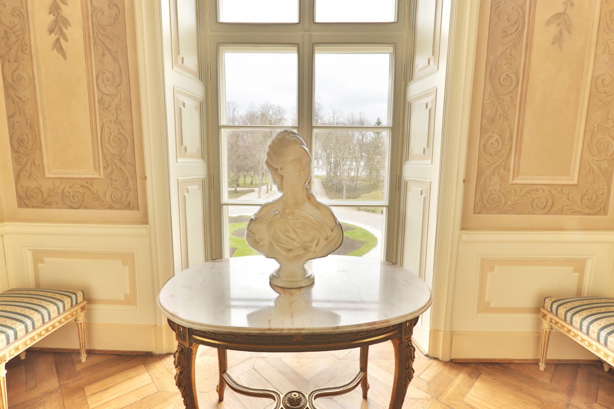 Gabinecik w Pałacu Myślewickim, na środkowej ścianie znajduje się okno, pośrodku pomieszczenia znajduje się stół, na którym stoi popiersie. 