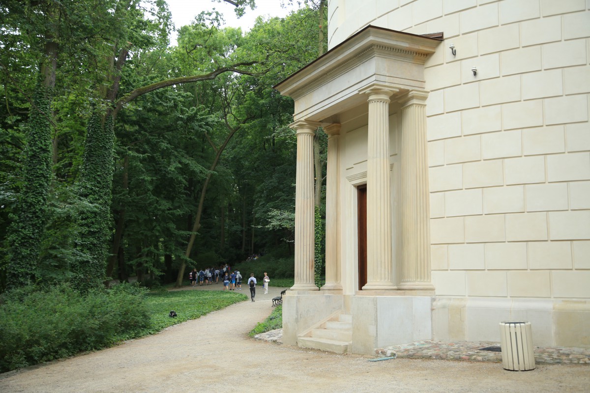 Wodozbiór w Łazienkach Królewskich - okrągły biały budynek, na środku drzwi z kolumnowym portykiem.
