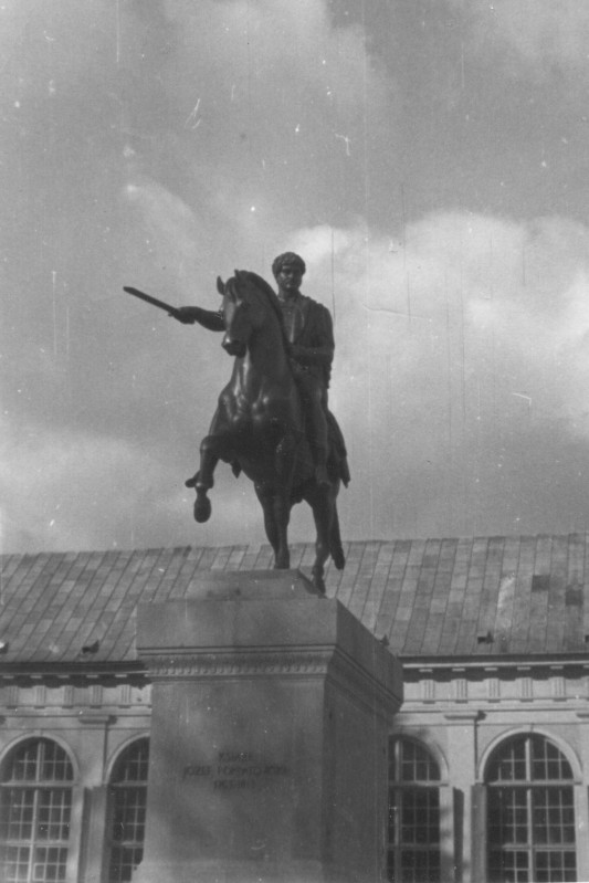 Pomnik przedstawiający mężczyznę na koniu, w tle widać budynek.