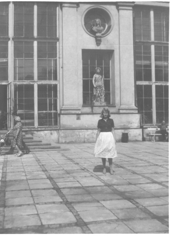 Kobieta stojąca przed budynkiem.