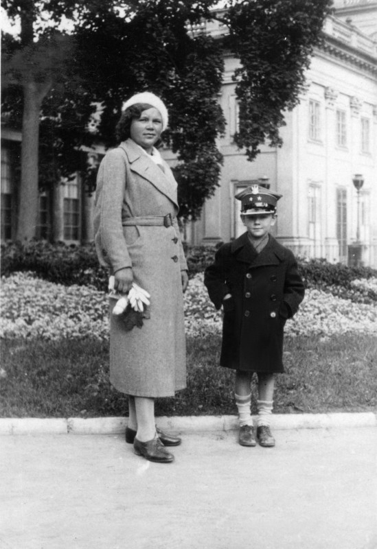 Kobieta z chłopcem stoi na tle budynku w Łazienkach Królewskich.