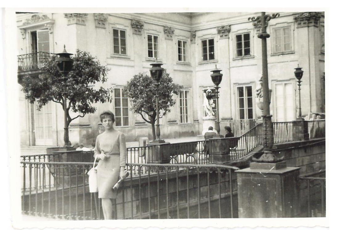 Kobieta stoi na mostku przy Pałacu na Wyspie w Łazienkach Królewskich.