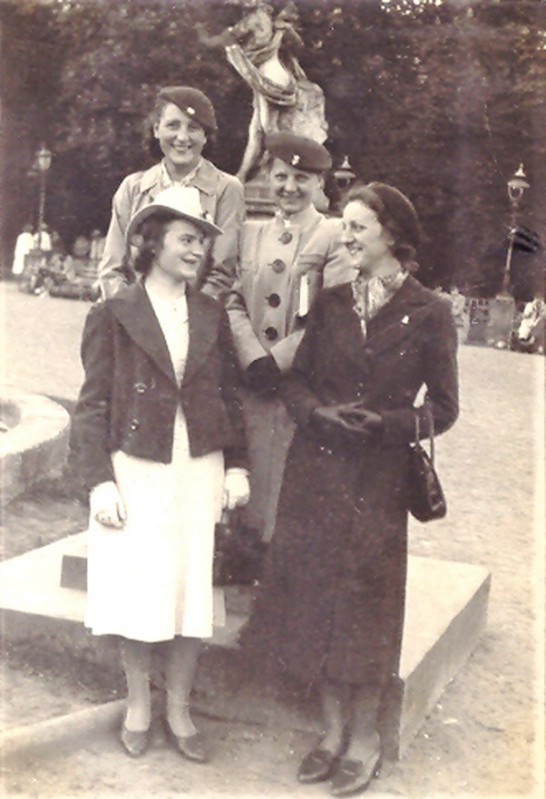 Archiwalne zdjęcie przedstawiające cztery kobiety stojące przed niewielką rzeźbą w Łazienkach Królewskich. 
