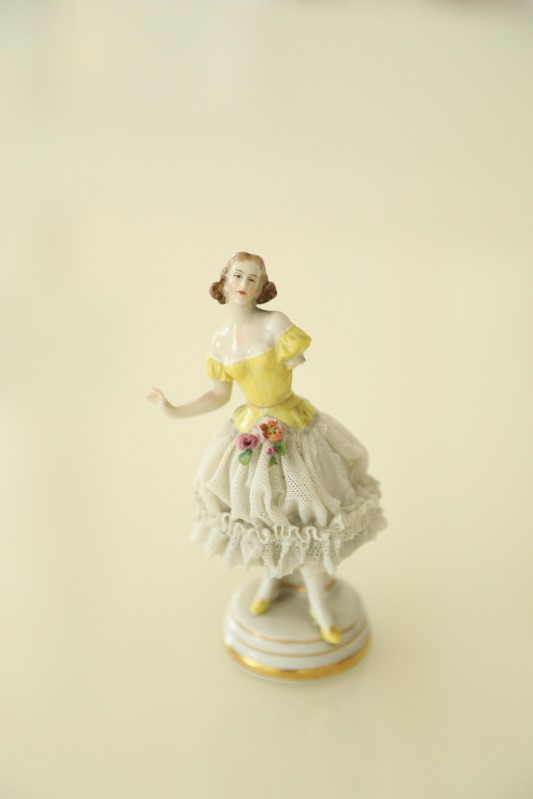 Porcelanowa figurka tancerki w żółtej sukience.