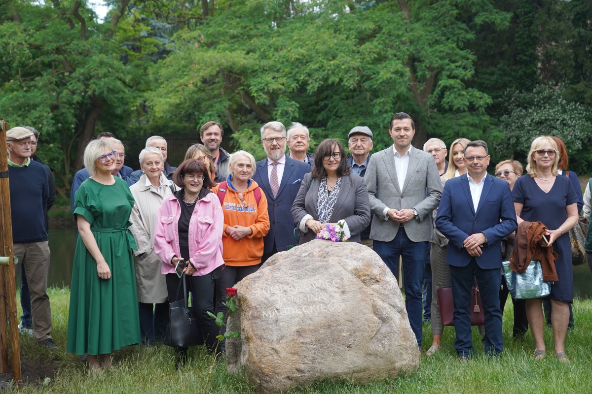 Grupa ludzi stoi przy kamieniu i pozuje do zdjęcia.