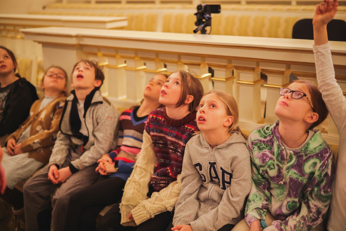 Dzieci siedzą na widowni teatru. 