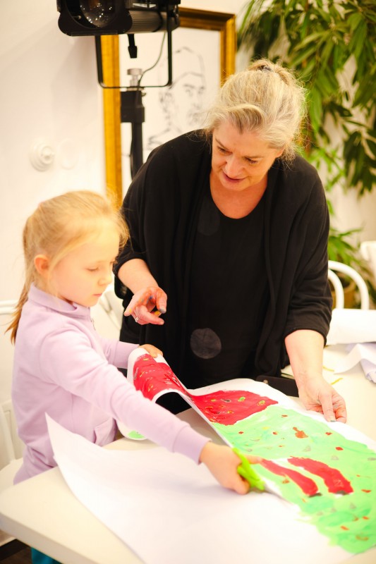 Dziecko maluje obrazek, obok stoi kobieta. 