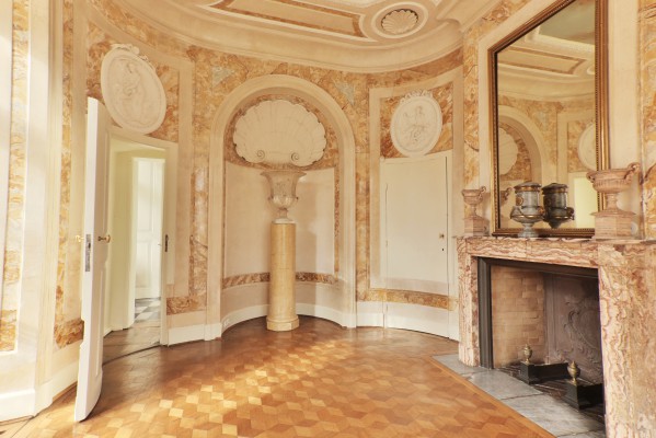 Łazienka w Pałacu Myślewickim, po prawej stronie znajduje się kominek, na którym wisi lustro, na kominu stoją wazy.
