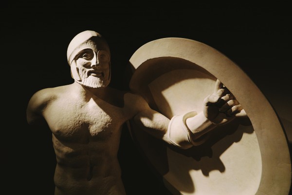 Rzeźba przedstawiająca starożytnego wojownika, trzymającego w jednej ręce tarczę. 
