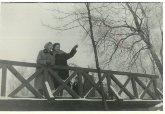 Dwie kobiety stoją na moście w zimowej aurze.