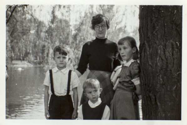 Kobieta i troje dzieci stoją obok drzewa, w tle widać staw. 