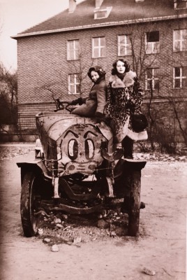 Dwie kobiety siedzą na starym wozie strażackim. 