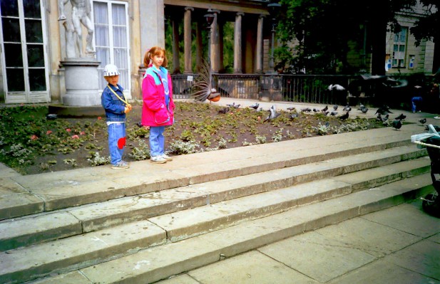 Dziewczyna i chłopczyk stoją na schodach przed budynkiem.