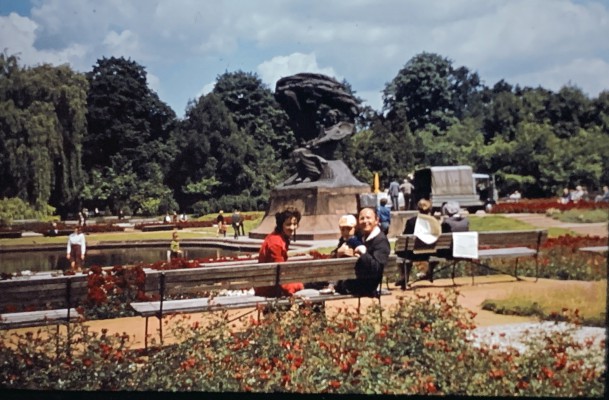 Kobieta i dziecko w ogrodzie. W tle widoczny jest Pomnik Fryderyka Chopina.