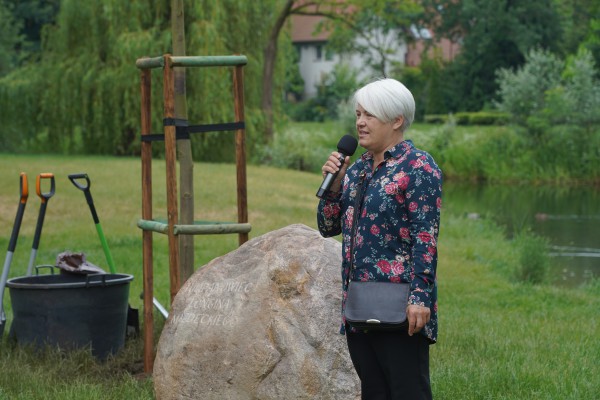 Kobieta stoi przy kamieniu z mikrofonem w ręku.
