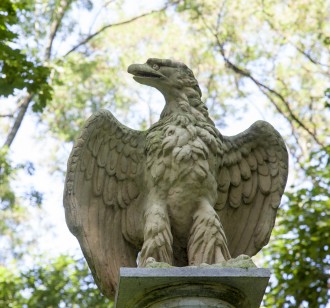 Rzeźba orła na tle drzew.