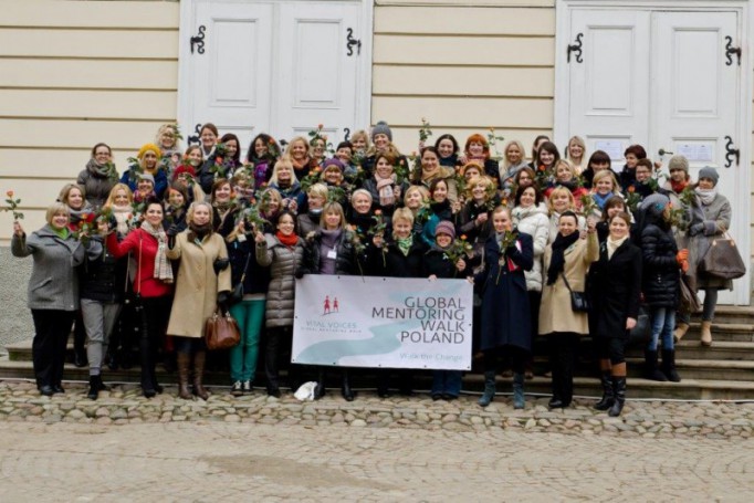 Kilkadziesiąt kobiet stoi przed budynkiem, pozując do pamiątkowego zdjęcia.