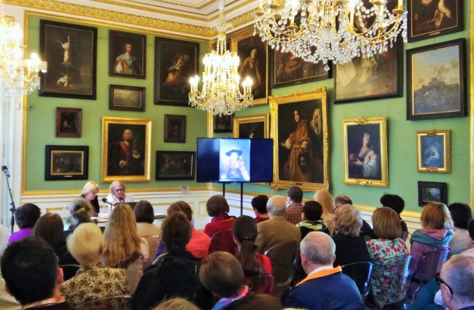 Ludzie siedzą w Galerii Obrazów w Pałacu na Wyspie w Łazienkach Królewskich i słuchają wykładu.