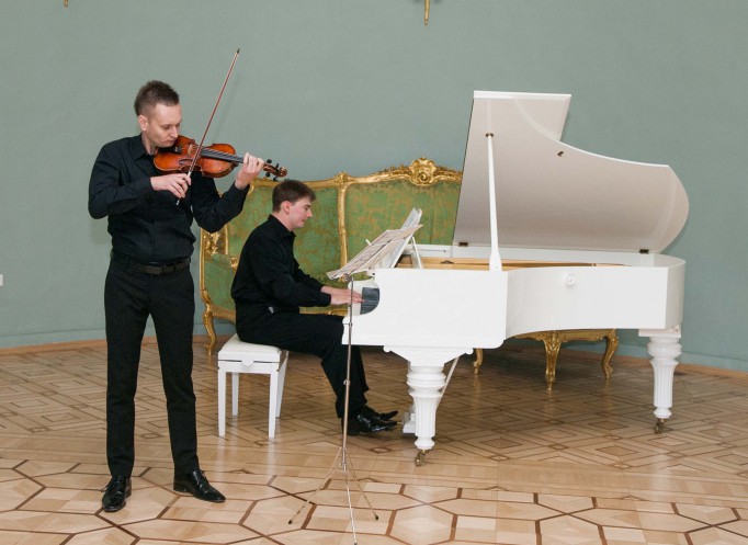 Koncert, podczas którego jeden mężczyzna gra na fortepianie, a drugi na skrzypcach. 