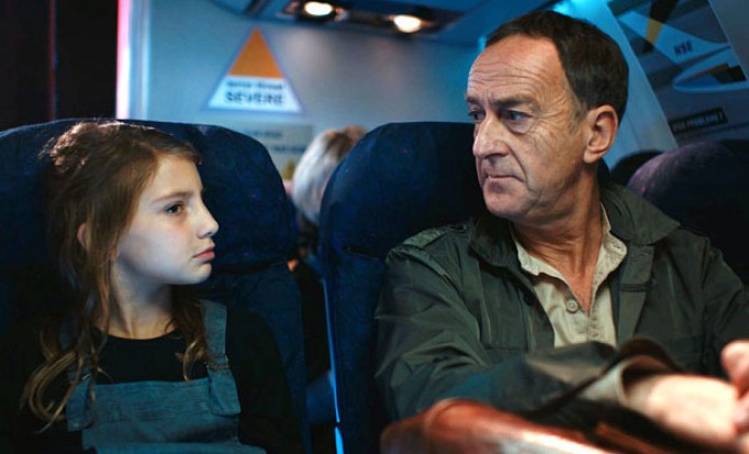 Kadr z filmu "Wielka klęska Europy", dziewczynka siedzi obok mężczyzny w samolocie i z nim rozmawia.