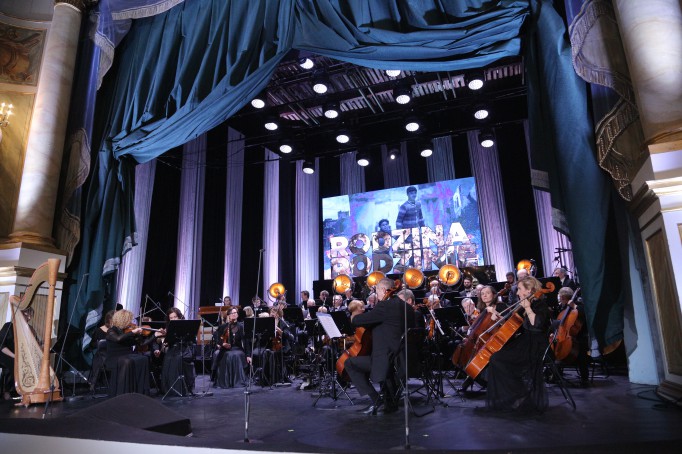 Orkiestra gra na scenie podczas koncertu.