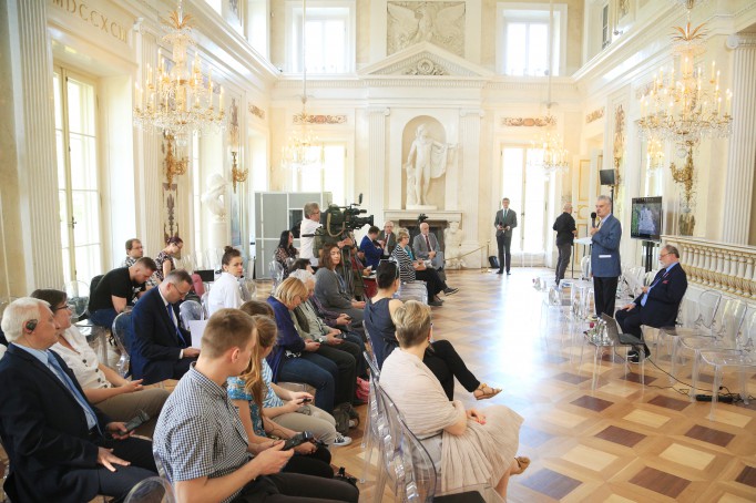 Konferencja w Sali Balowej Pałacu na Wyspie, ludzie siedzą na krzesłach, prelegenci przemawiają, stojąc przed mikrofonem.