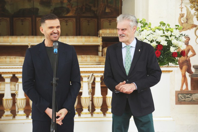 Jeden z mężczyzn, projektant Maciej Zień, stoi przed mikrofonem, drugi - dyrektor Muzeum Łazienki Królewskie - obok.