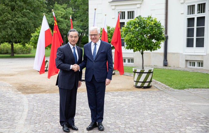 Minister Wang Yi i minister Jacek Czaputowicz stoją przed Pałacem Myślewickim i ściskają sobie dłonie.