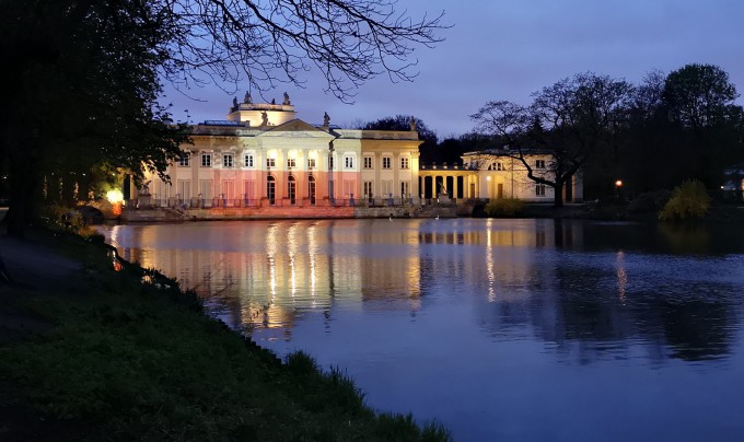 Pałac na Wyspie nocą, oświetlony iluminacją w biało-czerwonych barwach.