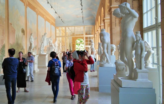 Zwiedzający w Królewskiej Galerii Rzeźby oglądają marmurowe posągi. 