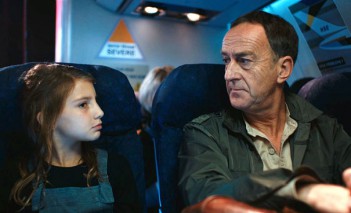 Kadr z filmu "Wielka klęska Europy", dziewczynka siedzi obok mężczyzny w samolocie i z nim rozmawia.