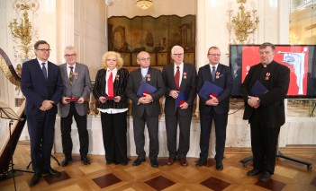 Kobieta i czterech mężczyzn stoją pod ścianą Sali Balowej Pałacu na Wyspie, w rękach trzymają teczki.