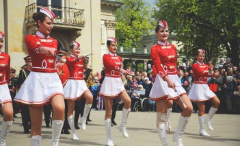 Parada przed Pałacem na Wyspie. Kobiety ubrane w biało-czerwone stroje maszerują. 