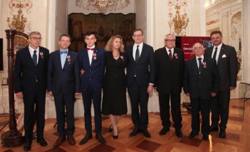 Grupa kilku osób z orderami przypiętymi do piersi stoi i pozuje do zdjęcia.