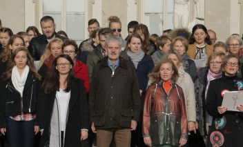 Grupa osób stoi obok siebie na baczność i śpiewa.
