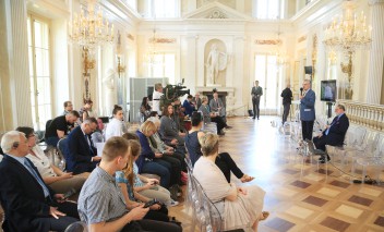 Konferencja w Sali Balowej Pałacu na Wyspie, ludzie siedzą na krzesłach, prelegenci przemawiają, stojąc przed mikrofonem.