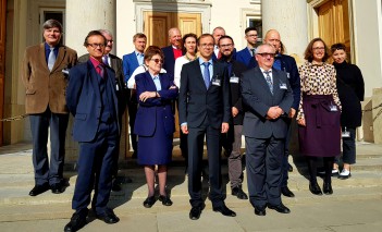 Grupa osób stoi przed wejściem do Płacu na Wyspie, odwrócona tyłem do pałacowych kolum, tuż przy drzwiach.