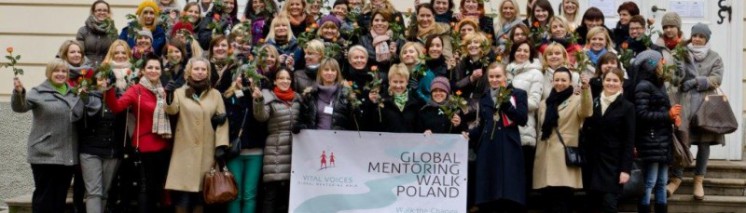 Kilkadziesiąt kobiet stoi przed budynkiem, pozując do pamiątkowego zdjęcia.