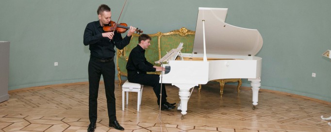 Koncert, podczas którego jeden mężczyzna gra na fortepianie, a drugi na skrzypcach. 