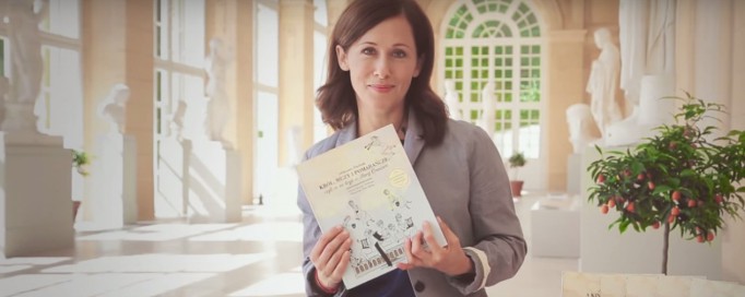 Aktorka Jolanta Fraszyńska siedzi w Starej Oranżerii i trzyma przed sobą książkę.