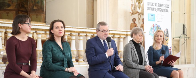 Kobieta, mężczyzna i dwie kobiety siedzą obok siebie na krzesłach.