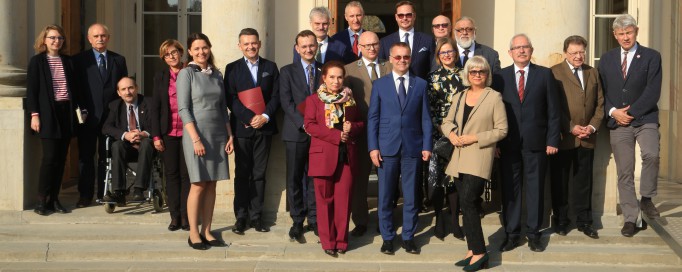 Grupa osób stoi na schodach przed Pałacem na Wyspie i pozuje do zdjęcia.
