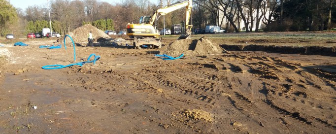 Plac budowy, na którym w dali stoi koparka.
