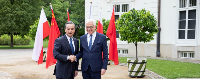 Minister Wang Yi i minister Jacek Czaputowicz stoją przed Pałacem Myślewickim i ściskają sobie dłonie.