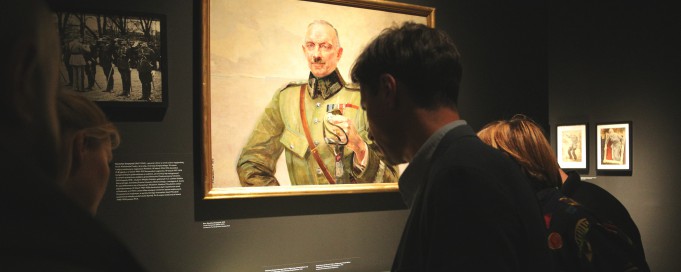 Wystawa "Virtuti Militari" Kilka osób stoi przed szklaną gablotą i ogląda pamiątki.